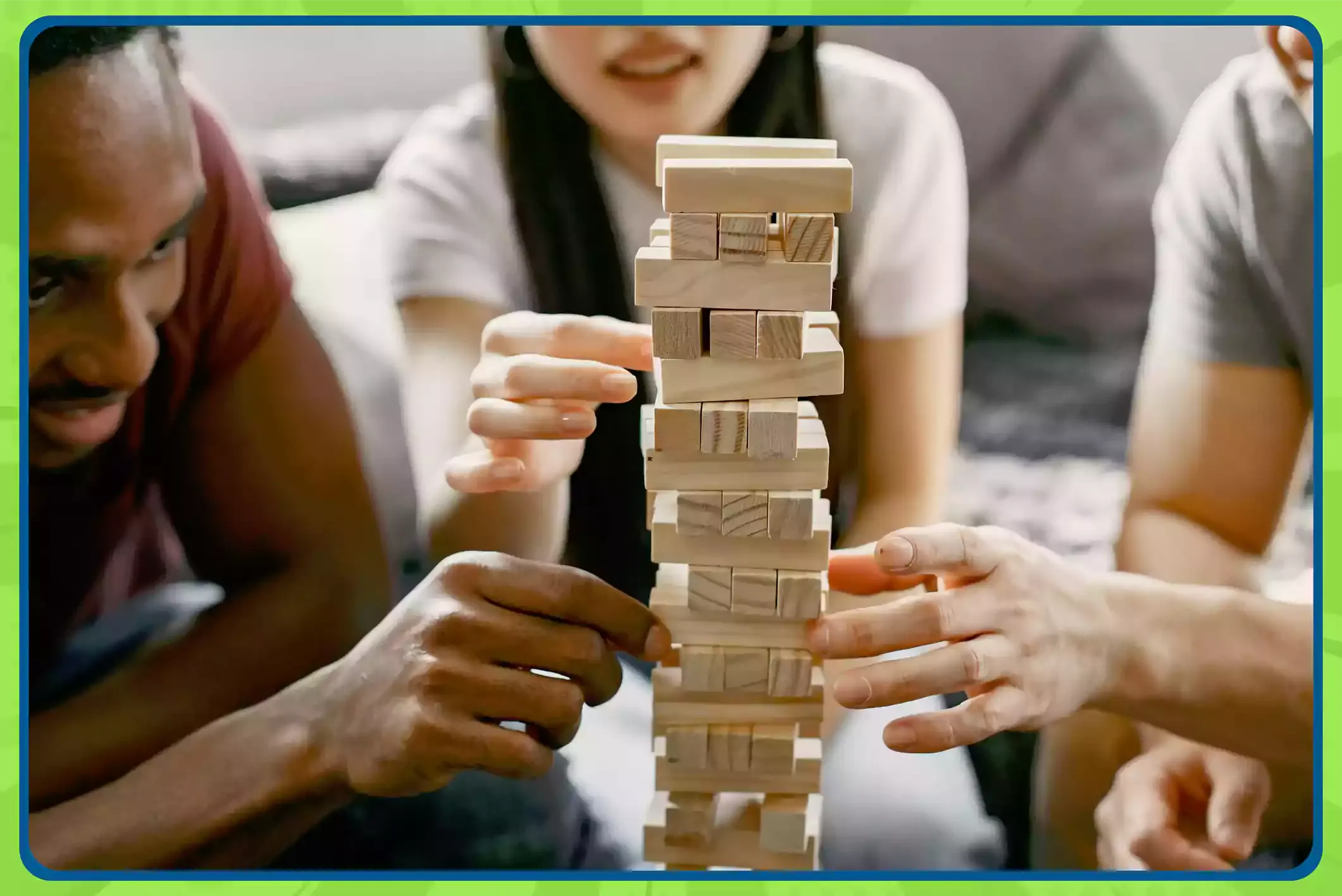 Three people play Jenga together, carefully pulling wooden blocks from a stacked tower.