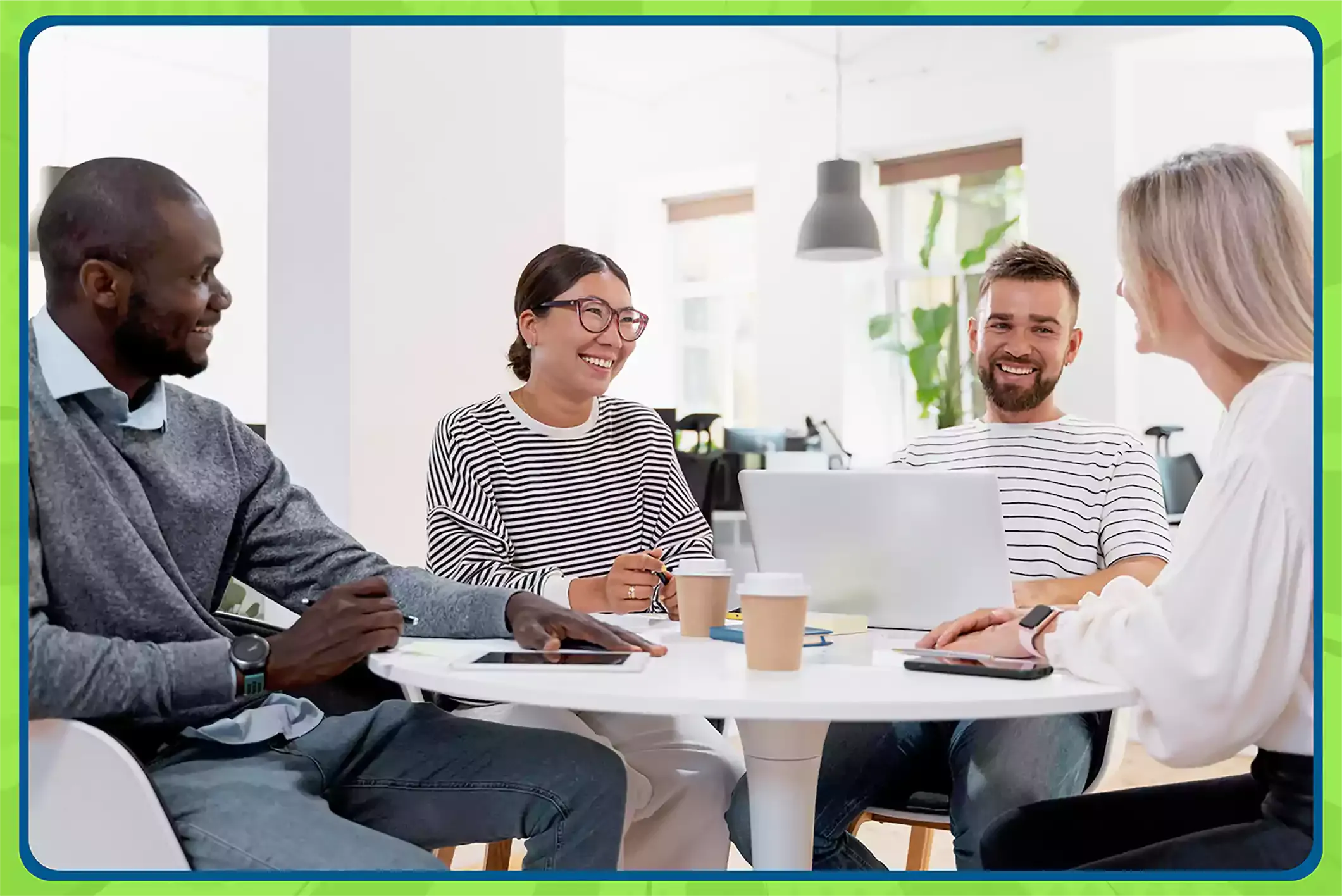 Four coworkers sit around a table, smiling while playing a speed networking game for teams in office.